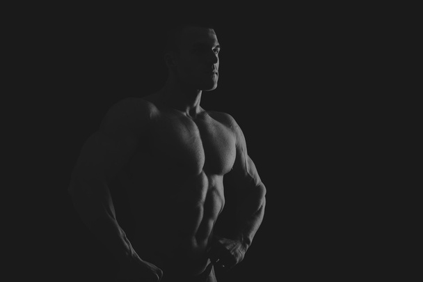Silhouette di bodybuilder su uno sfondo scuro
. - Foto, immagini