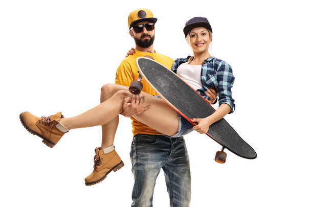 Bearded man carrying a female skater with a longboard - Foto, afbeelding