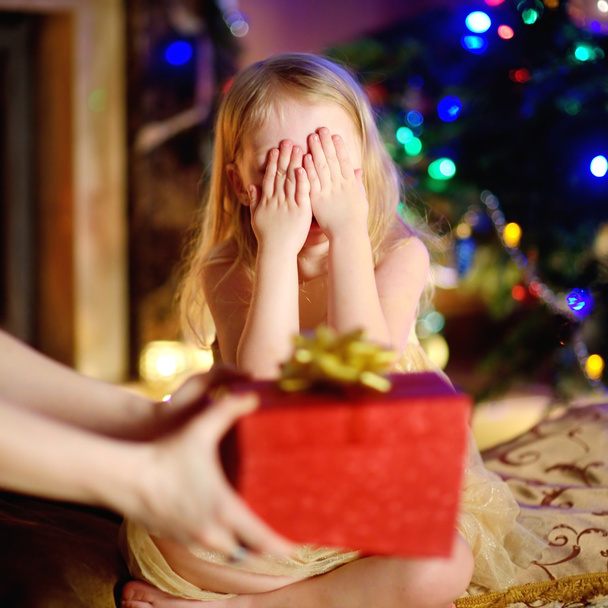 Happy little girl getting a Christmas gift from her mommy - Фото, изображение