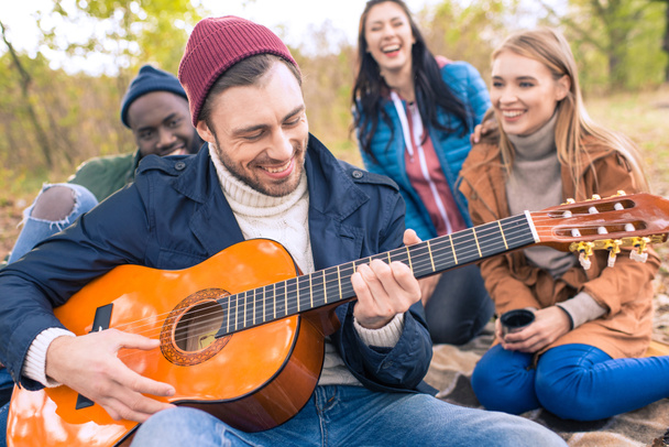 Amigos disfrutando de la guitarra en otoño parque
 - Foto, Imagen
