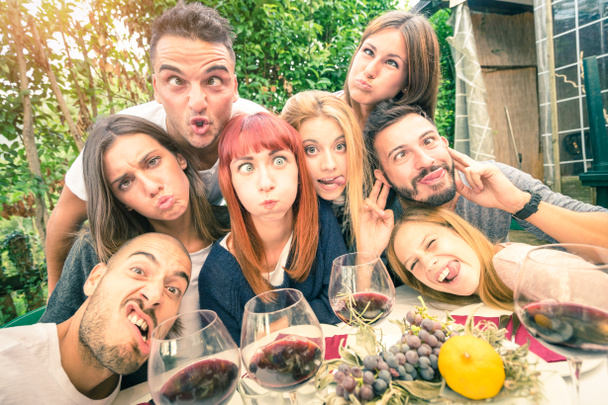 beste Freunde beim Selfie im Freien mit Hintergrundbeleuchtung - fröhliches Jugendkonzept mit jungen Leuten, die gemeinsam Wein trinken - Heiterkeit und Freundschaft bei der Weinlese - weicher entsättigter Filter - Foto, Bild