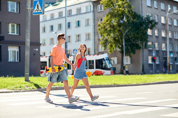 teenage couple with skateboards on city street - Foto, afbeelding