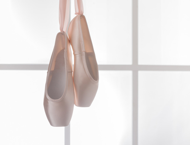 Pinkfarbene Ballett-Spitzenschuhe hängen am Fenster - Foto, Bild