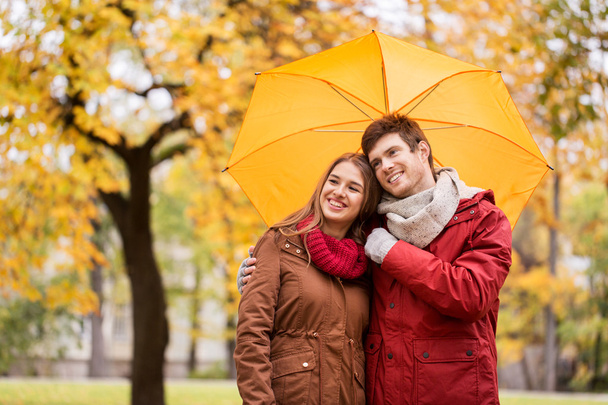 smiling couple with umbrella in autumn park - Фото, изображение