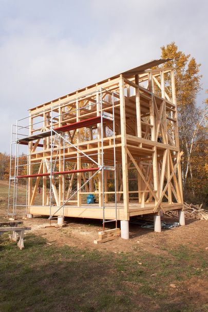 Metal scaffolding around the unfinished house.  Construction of ecological house. Wooden frame of house under construction.Framed New Construction of a House. Timber house in building process - Photo, Image