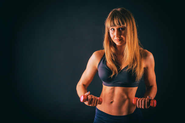 Vrouwelijke fitness op een donkere achtergrond. - Foto, afbeelding
