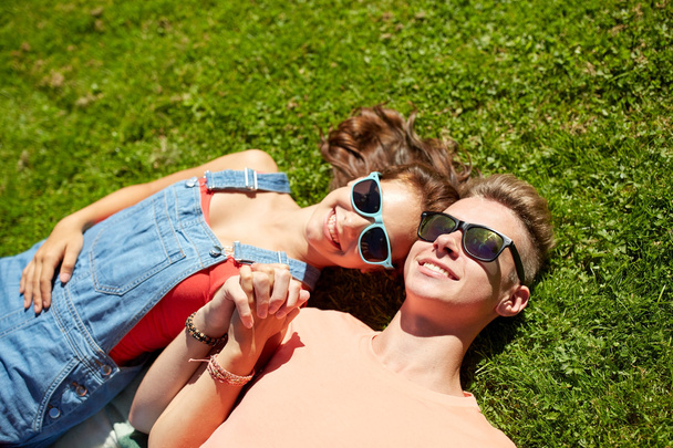 happy teenage couple lying on grass at summer - Fotografie, Obrázek