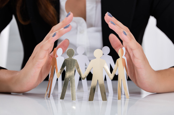 Businesswoman Hands Protecting Cut-out Figures - Foto, afbeelding