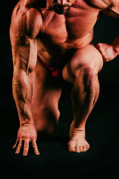 Fisiculturista muscular saudável em um fundo preto
 - Foto, Imagem