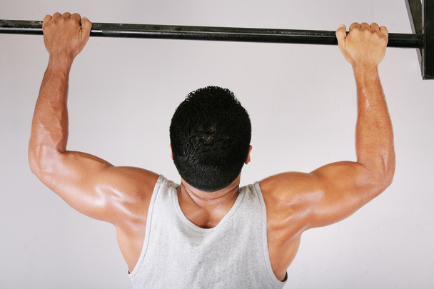 Reaching Goal: Strong man doing pull-ups on a bar in a gym - Photo, Image