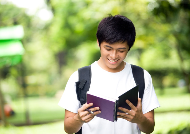 Asian young handsome guy open a book and smile in the park - Fotoğraf, Görsel