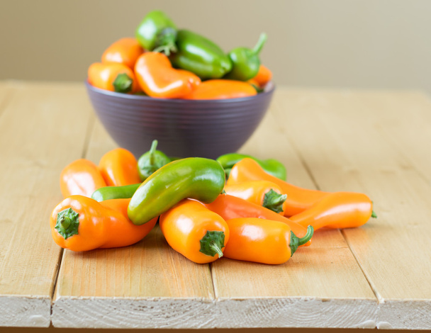 Colorful bell peppers in a bowl on a wooden table. - Photo, Image