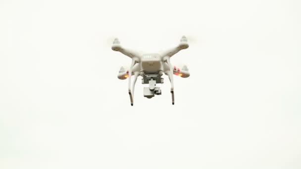 Drone blanco, quadrocopter, con cámara fotográfica volando en el cielo azul
 - Metraje, vídeo