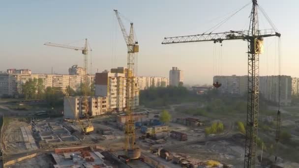 Industriële bouwkranen en silhouetten boven de zon bij zonsopgang - Video