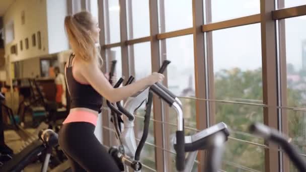 The girl working out with the simulator and looking out the window in the gym 4K - Séquence, vidéo