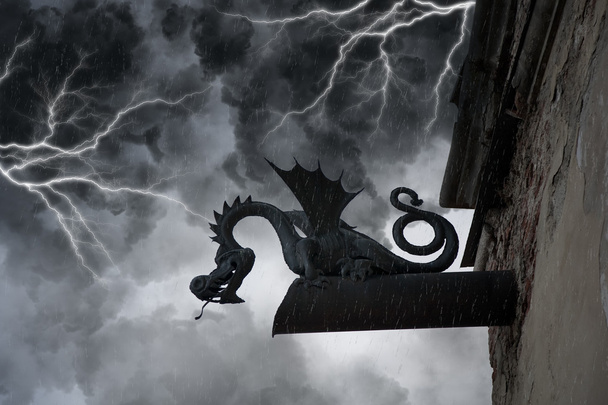 Furchterregende Chimäre an der Fassade des alten Schlosses unter Gewitterwolken und Blitzen - Foto, Bild