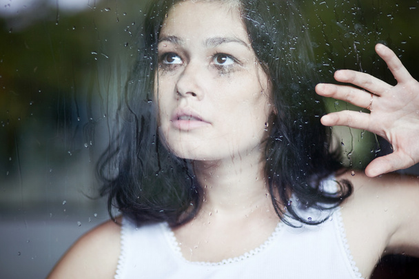 Θλιβερή γυναίκα κοιτάζει από το παράθυρο - Φωτογραφία, εικόνα