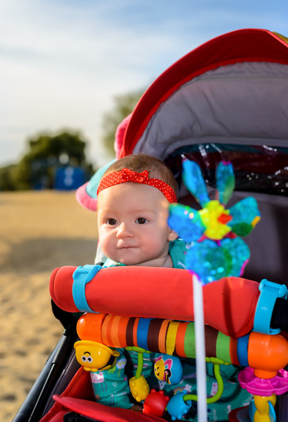 Χαριτωμένο μωρό κοριτσάκι σε πολύχρωμα καροτσάκι - Φωτογραφία, εικόνα