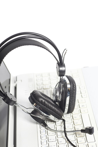 Kuulokkeet kannettavan tietokoneen näppäimistöllä.Viestintä käsite
 - Valokuva, kuva