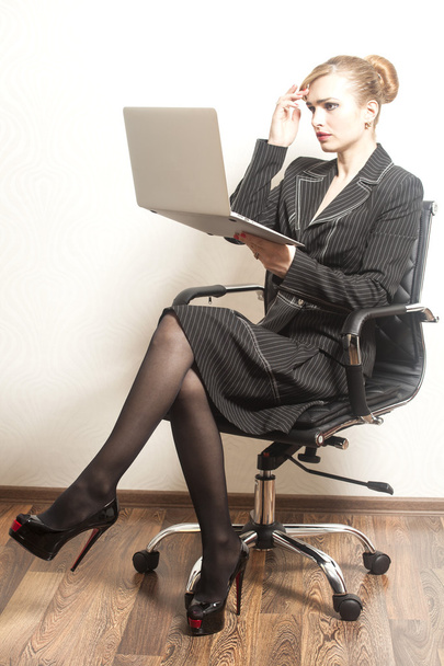 Businesswoman sits on chair and work on her laptop - Фото, зображення