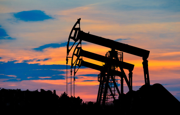 Silueta čerpadla ropy v ropném poli při západu slunce - Fotografie, Obrázek