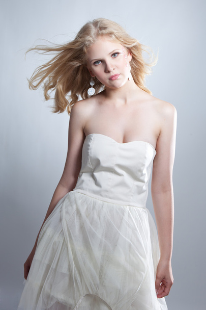 Young blonde girl posing in studio in white dress - Fotoğraf, Görsel