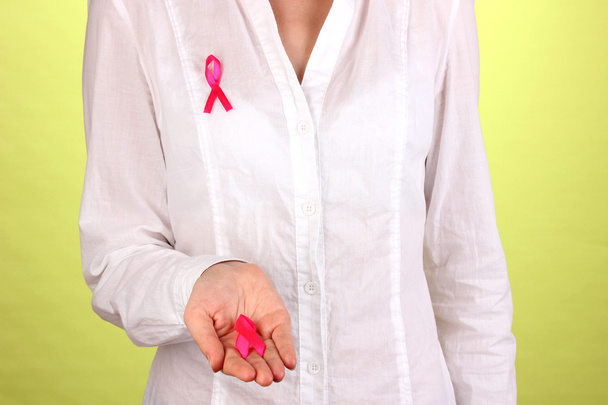 Woman with pink ribbon in hands on green background - Photo, Image