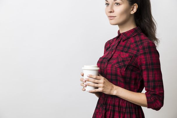 Side view of thoughtful young woman in red dress with coffee cup - Fotografie, Obrázek