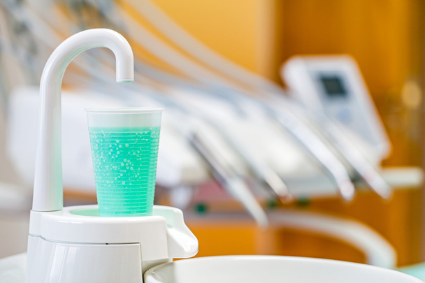 Vidro plástico com líquido de lavagem anti-séptico na cabine dentária
 - Foto, Imagem