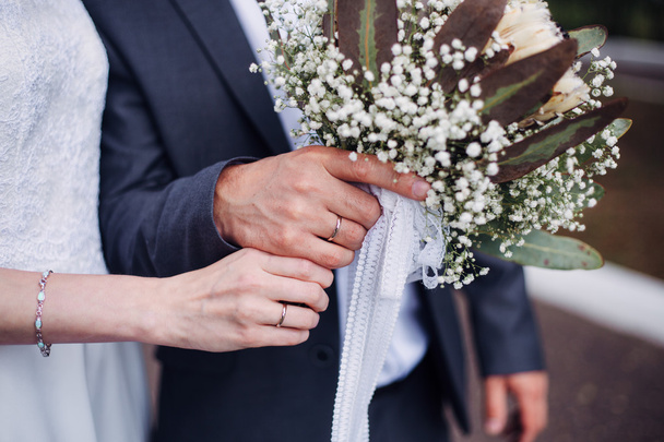 Hands and rings on wedding bouquet - Fotoğraf, Görsel