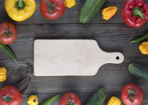 Cutting board and fresh vegetables on wooden table. - Фото, зображення