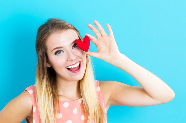 young woman holding heart cushion - Foto, afbeelding