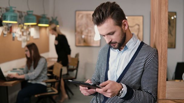 young handsome bearded man uses touchscreen tablet in the modern startup office. - Photo, Image