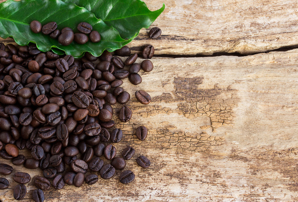 Coffee beans and green leaf on wooden background - Photo, Image