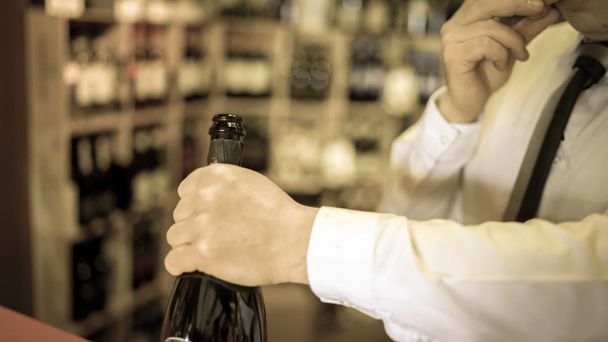 Sommelier uncorks a bottle of sparkling wine in a wine cellar. - Fotó, kép