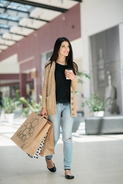 Attractive cute girl in with the shopping bags and warm drink in her hand - Foto, afbeelding