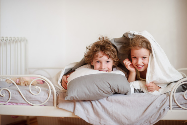Little brother and sister made a play on the bed in the bedroom. - Photo, image