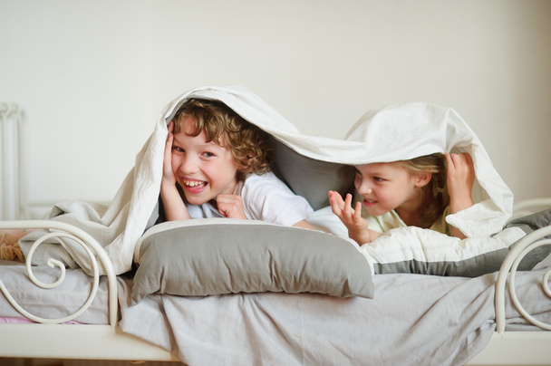 Little brother and sister made a play on the bed in the bedroom. - Fotoğraf, Görsel