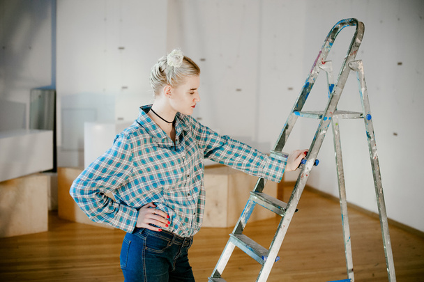 girl and construction ladder. studio shot of a young woman with a construction ladder in the room - Photo, Image