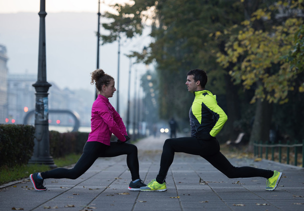 a young couple warming up before jogging - Φωτογραφία, εικόνα