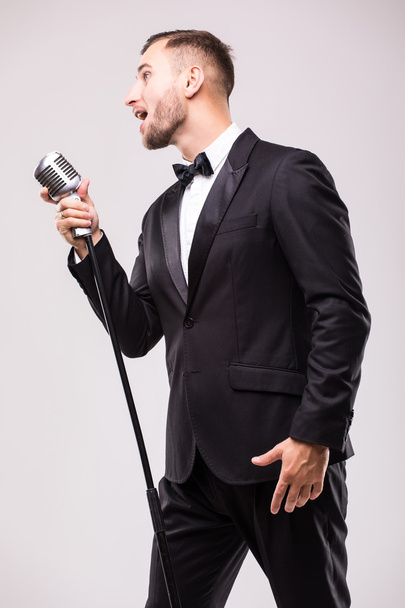 Young man in suit singing over the microphone - Zdjęcie, obraz
