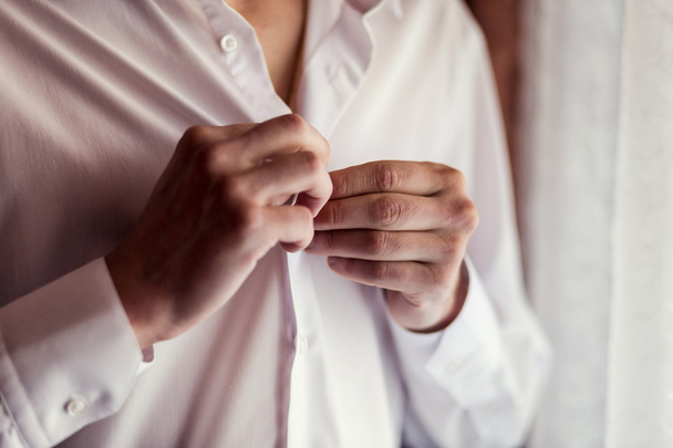 Επιχειρηματίας φόρεμα πουκάμισο. Ο άνθρωπος με το λευκό πουκάμισο στο το παράθυρο φόρεμα μανικετόκουμπα. Πολιτικός, ανδρικό στυλ, επιχειρηματίας κουμπώματος του πουκάμισο, αρσενικό χέρια closeup, Αμερικανός, Ευρωπαίος επιχειρηματίας - Φωτογραφία, εικόνα