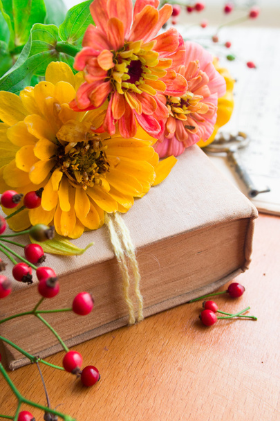 Old book with orange zinnia, key and autumn berries - Foto, imagen