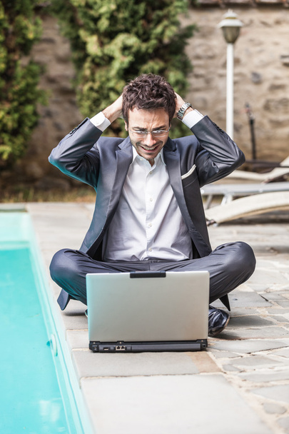 Young Businessman with Computer next to Swimming Pool - Фото, изображение