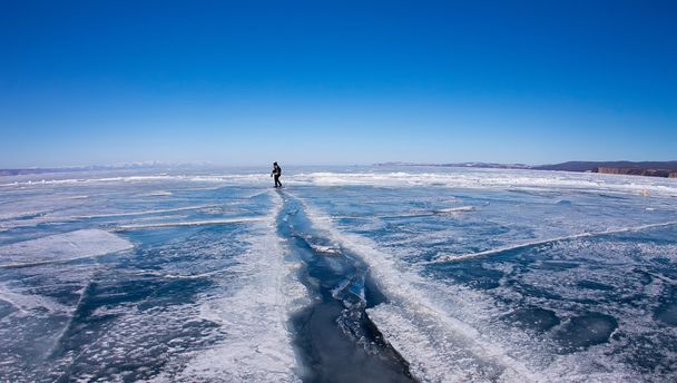 Man goes through a large crack in the ice of Lake Baikal - Fotoğraf, Görsel