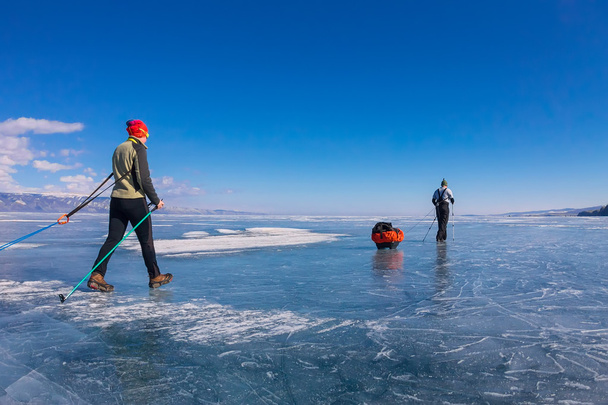 a woman and a man with a sledge and trekking pole is ice of Baik - Φωτογραφία, εικόνα