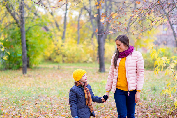 boy walking with his mother in autumn park - Foto, afbeelding