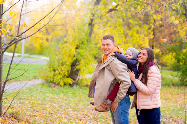 Mother and Father With Young Son On his back Autumn Park - Foto, imagen