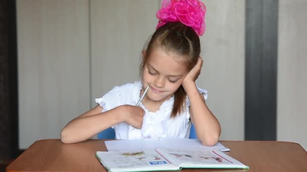 Μαθήτρια επταετή κορίτσι κάνει την εργασία που κάθεται στο τραπέζι στο σπίτι - Πλάνα, βίντεο