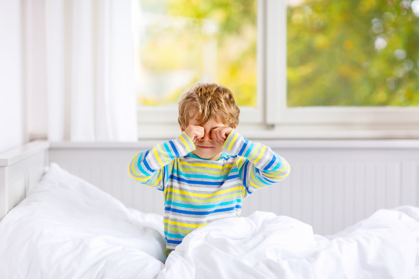 happy little kid boy after sleeping in bed in colorful nightwear - Фото, изображение